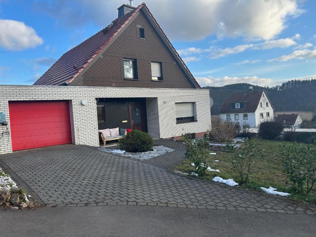 a brick house with a red garage at Ferienhaus Windrödel in Herzhausen