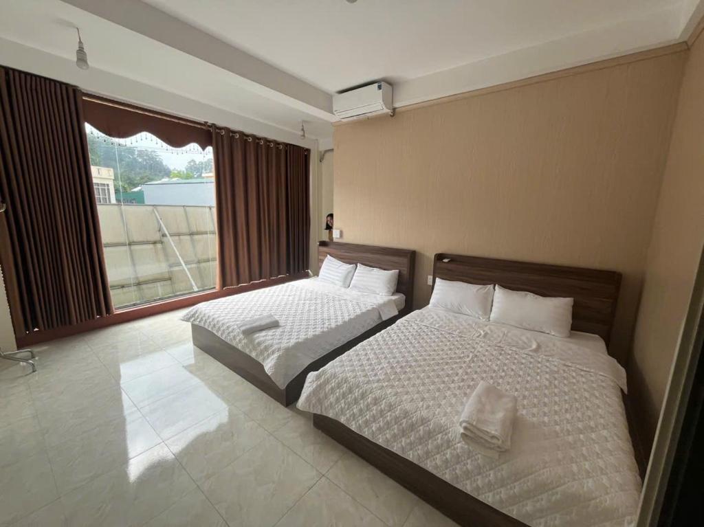 a bedroom with two beds and a large window at Thanh Thao Hostel - HaGiang Loop Tour in Làng Lap