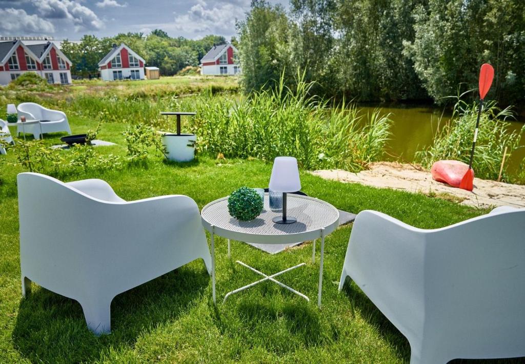 two white chairs and a table in the grass at Ferienhaus Pier 85 in Nordhorn