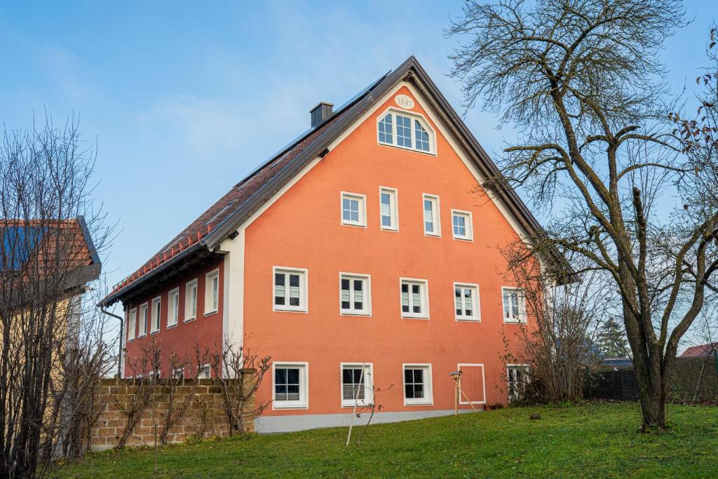 a large orange building with white windows and a tree at Ferienwohnung Demmelbach in Weil