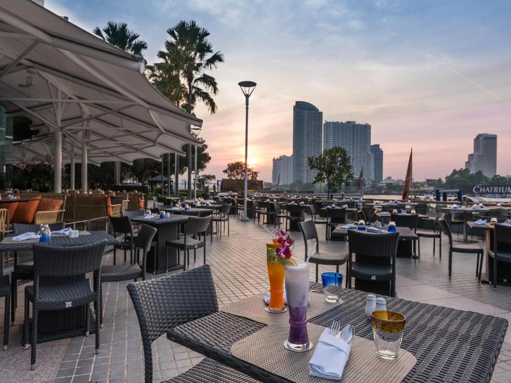 a restaurant with tables and chairs on a patio at Chatrium Hotel Riverside Bangkok in Bangkok