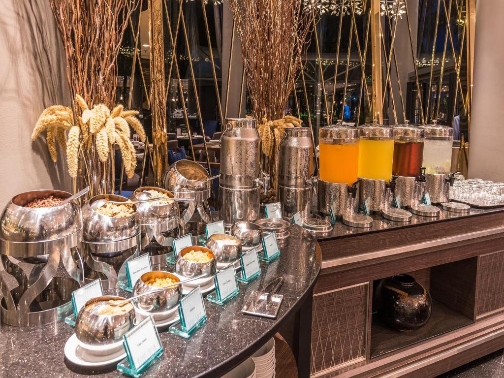 A breakfast buffet counter with covered dishes, drink dispensers and small food labels.