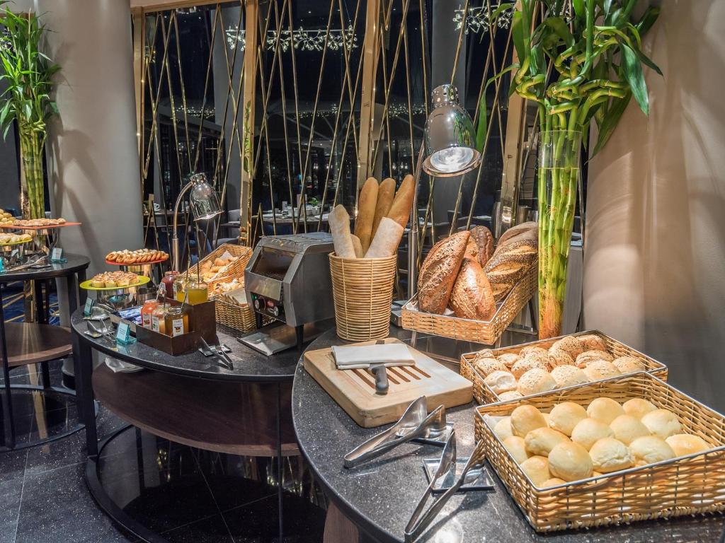 A bread-and-pastry station with baskets of rolls, sliced loaves and serving tongs.