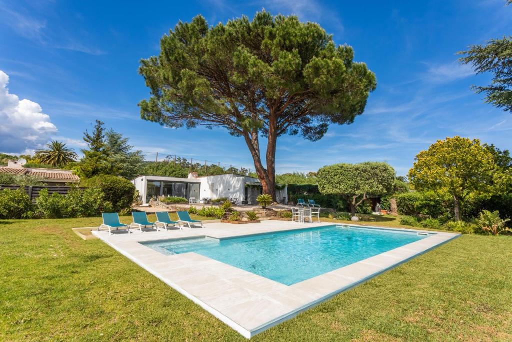 a swimming pool in a yard with chairs and a tree at Villa Artemis piscine Golfe St-Trop in Grimaud