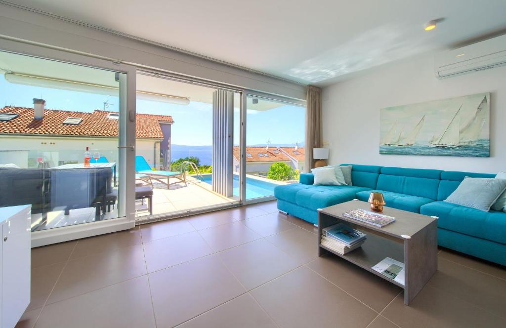 a living room with a blue couch and a view of the ocean at VILLA SOLIS LACUS modernes Apartment - privater beheizbarer Pool- Klimaanlage - private Parkplätze in Njivice
