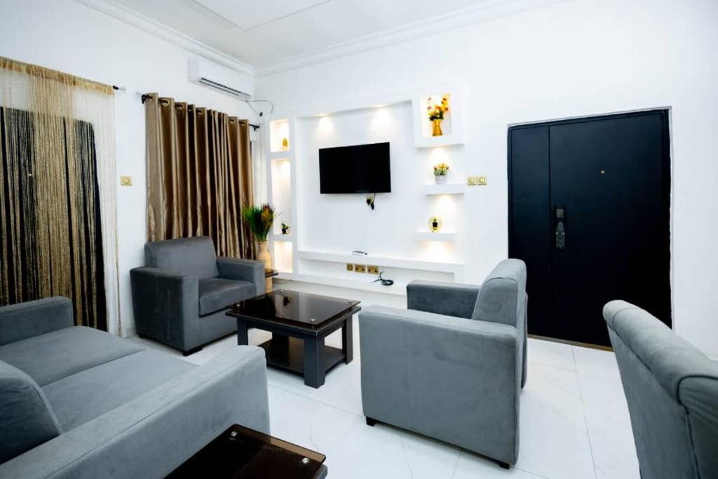 a living room with couches and a flat screen tv at Famous Apartments in Ologode