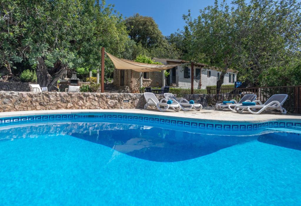 a swimming pool with chairs and a house at Can Miquel, villa in Pollensa in Pollença