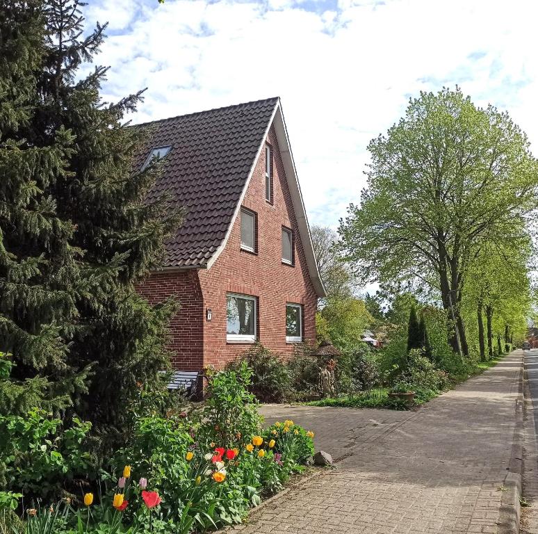 a red brick house with a tree and flowers at Fewo Apfel Striep in Steinkirchen