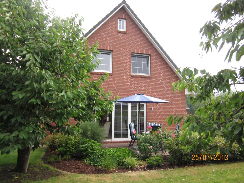 a red brick house with a table and an umbrella at Ferienhaus Minners in Jork
