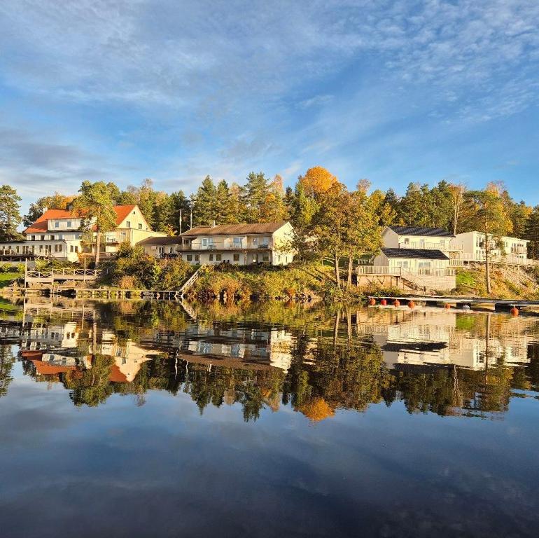 a lake with houses and trees reflecting in the water at Håveruds hotell och konferens in Håverud