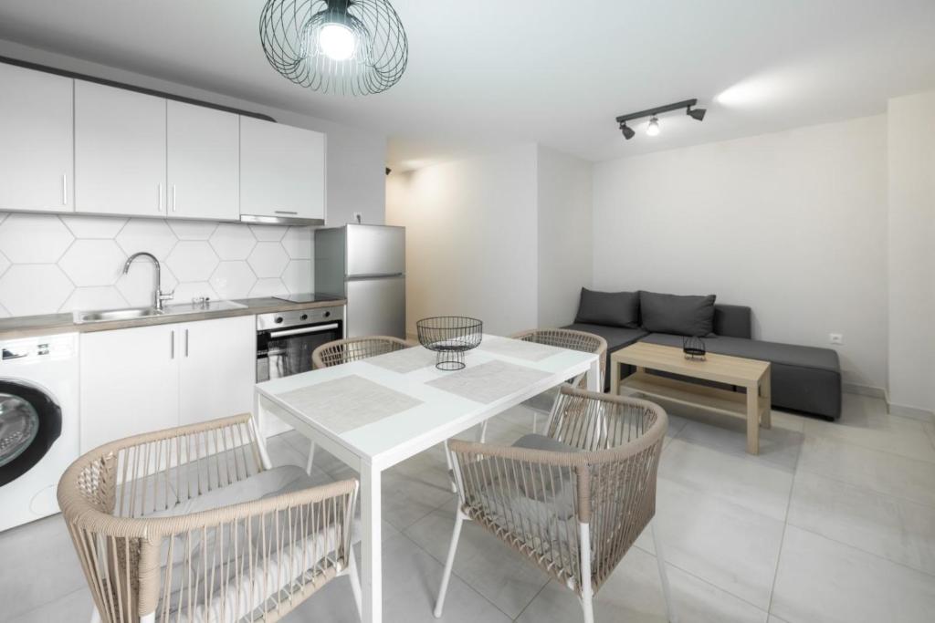 a kitchen and living room with a white table and chairs at DION APARTMENTS in Paleros