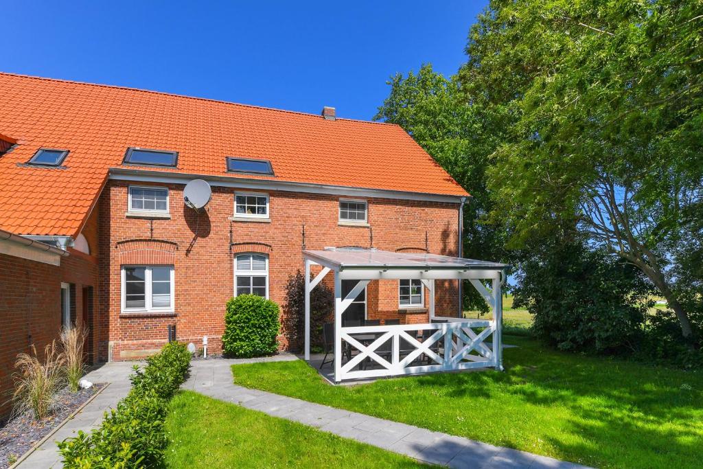 a gazebo in front of a brick house at Ferienwohnung Landleben am Meer in Bensersiel