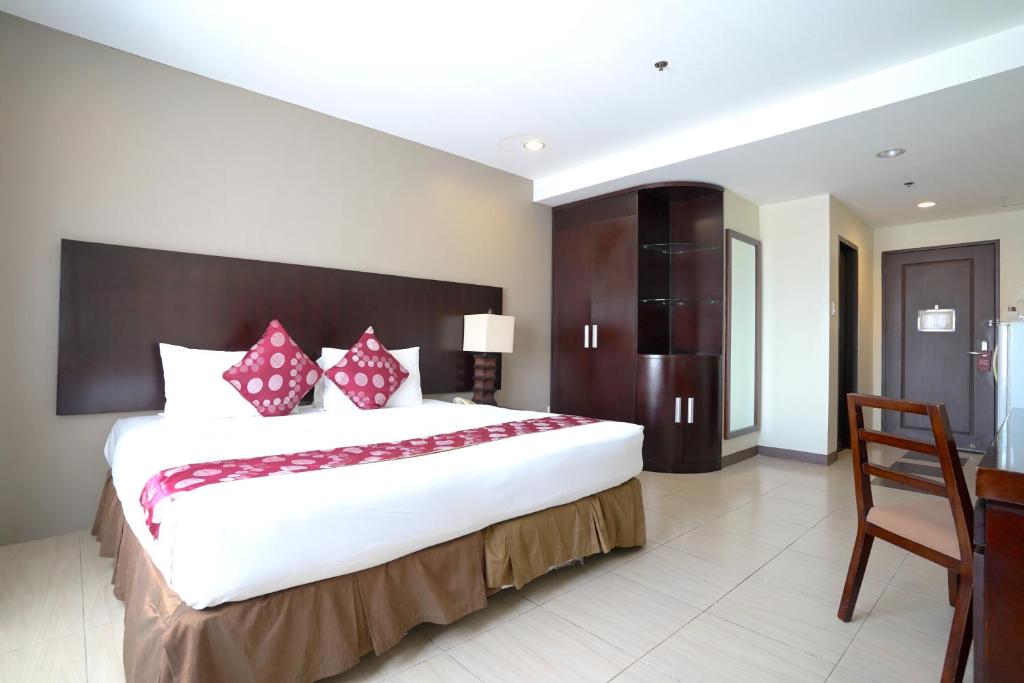 a large bedroom with a large bed with red pillows at Alpa City Suites Hotel in Cebu City
