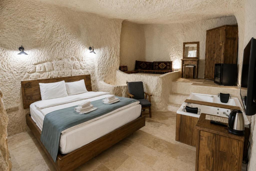 a bedroom with a bed and a desk and a television at Kayaharman cave otel in Nar