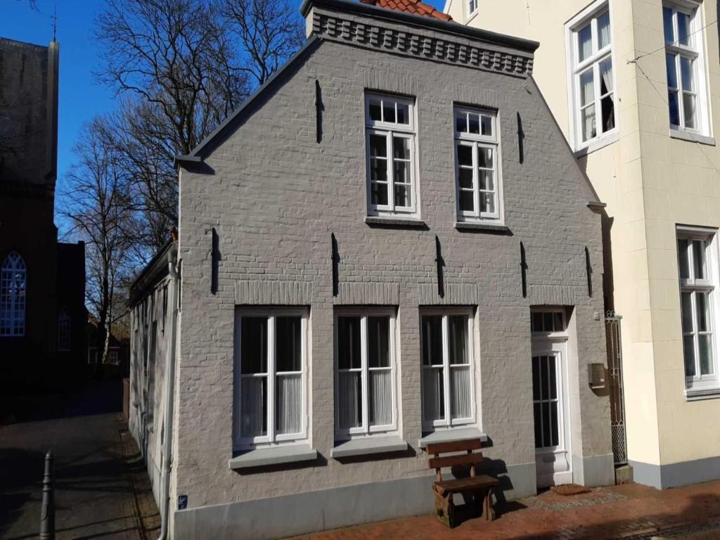 a gray house with white windows and a bench in front at Ferienwohnung am Kirchplatz 25561 in Weener