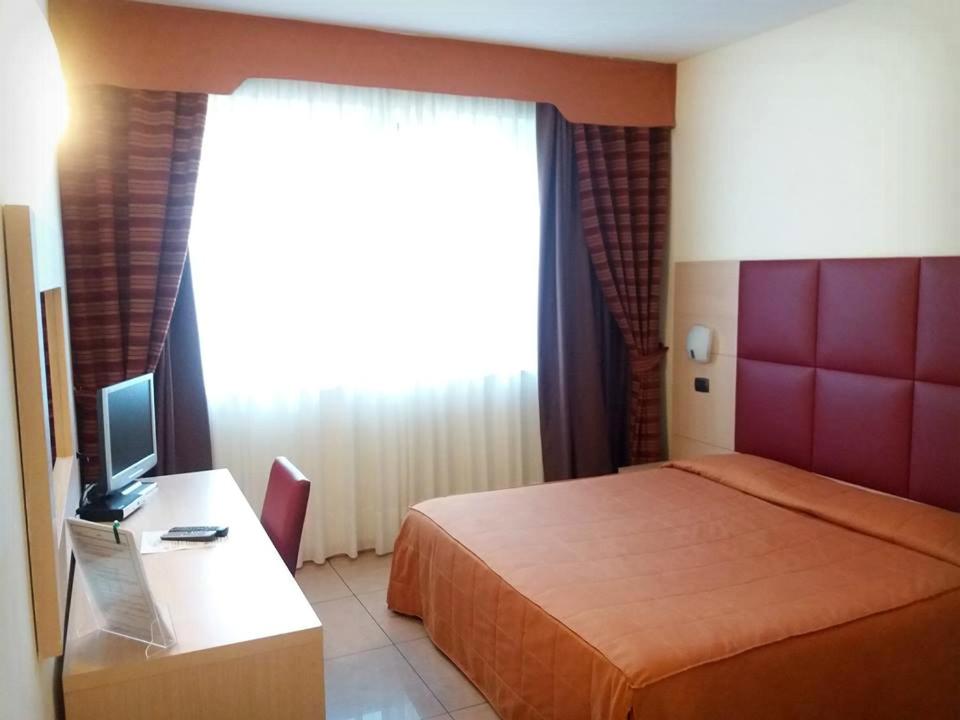a bedroom with a bed and a desk with a television at Hotel Panorama in Cambiano
