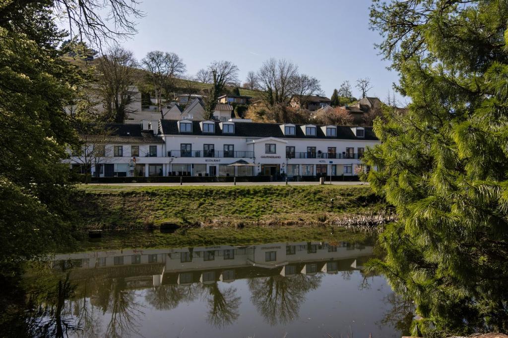 ein großes weißes Haus, das neben einem Gewässer steht in der Unterkunft Hotel Gulpenerland in Gulpen-Wittem