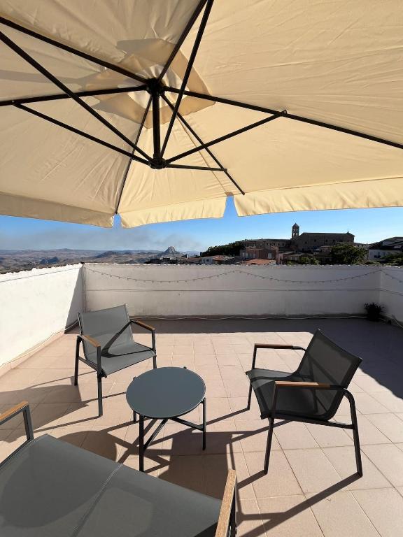 a patio with two chairs and a table and an umbrella at Casa Manzoni- Appartamento con terrazzo in centro in Mussomeli
