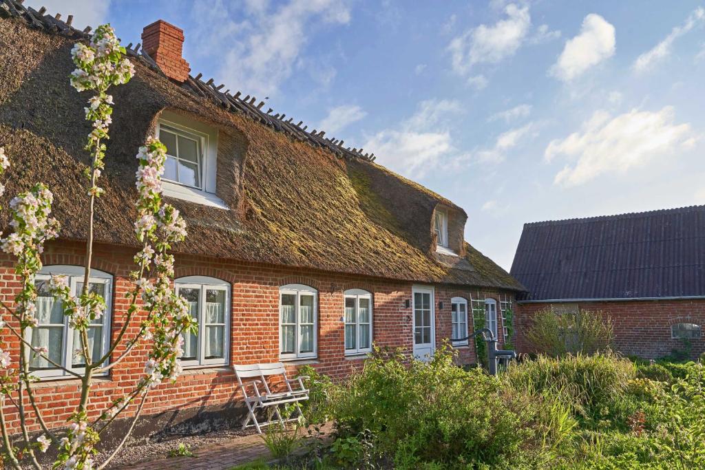 an old brick house with a grass roof at Reetdachhaus De Ole Kaat in Niesgrau
