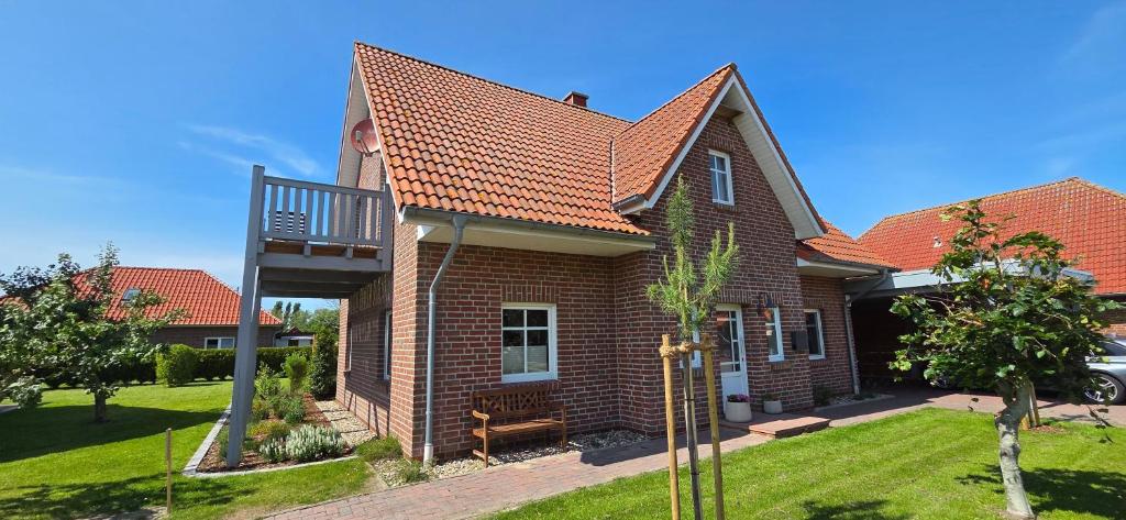 a brick house with a balcony and a yard at Nr 200 - Ferienwohnung Süderriff in Neuharlingersiel