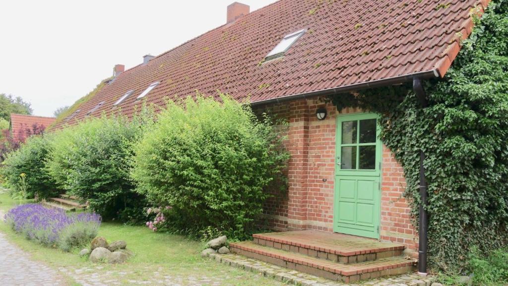 a red brick house with a green door and stairs at Unterm Dach in Ulrichshusen