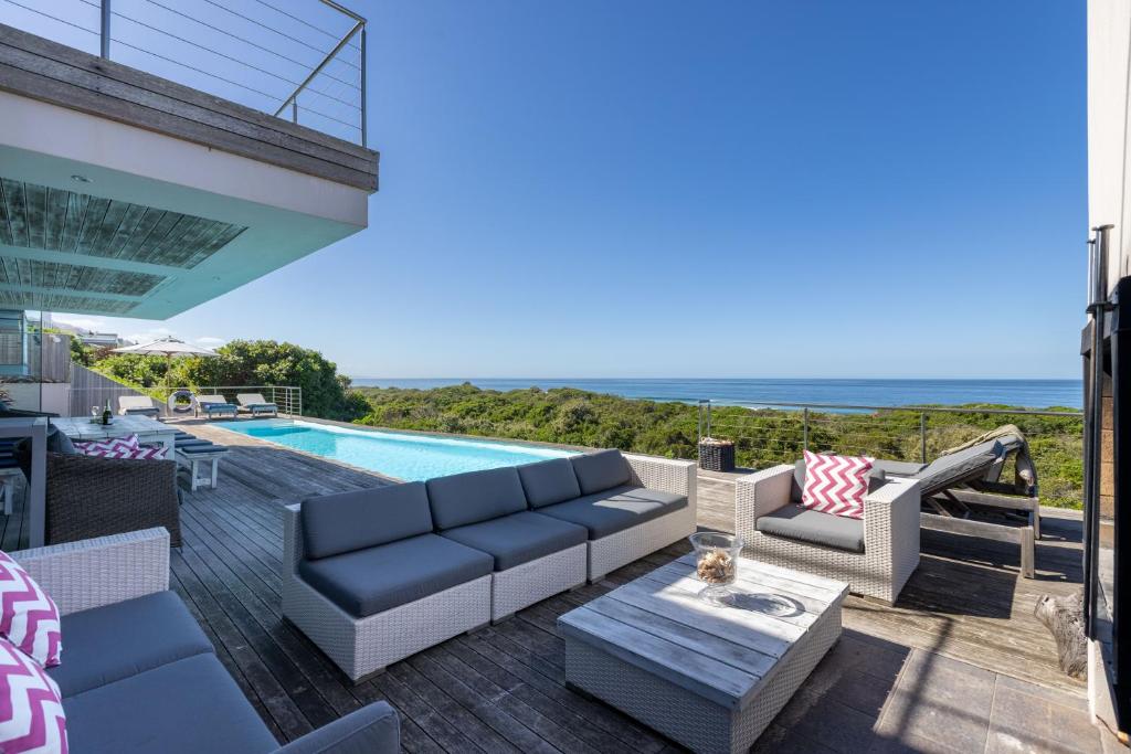 a patio with a couch and a table and a pool at Seascape in Plettenberg Bay