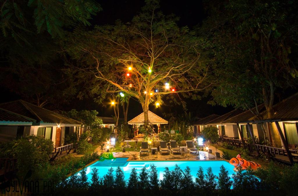 a swimming pool at night with a tree and lights at The Sylvana Pai in Pai