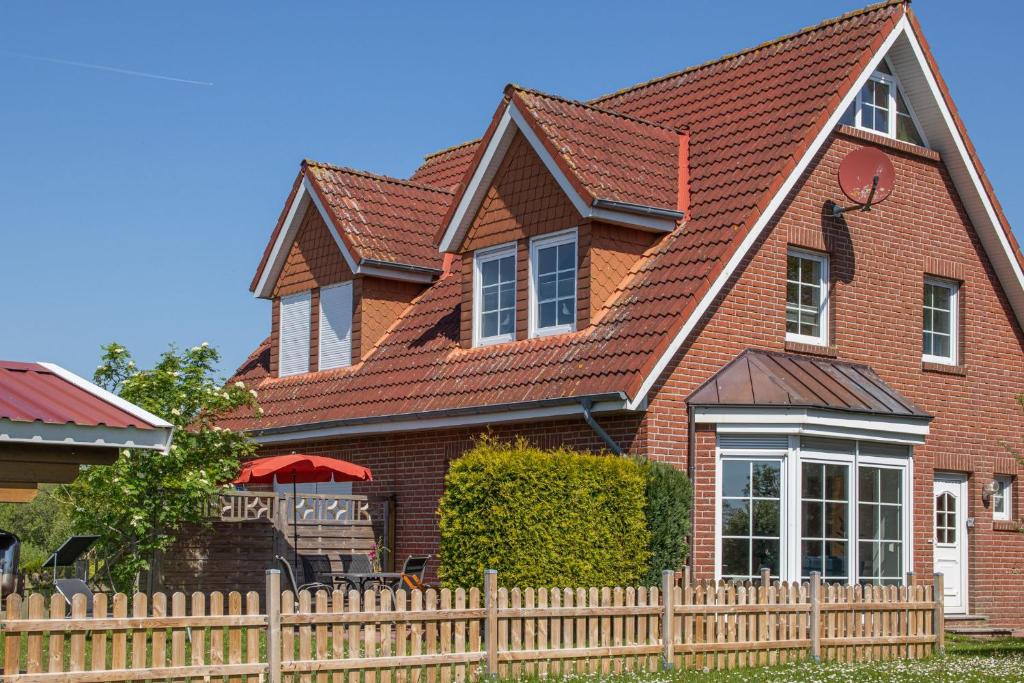 a brown brick house with a wooden fence at Ferienhaus Robby in Stedesdorf