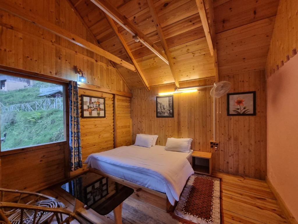 a bed in a wooden room with a window at Mid Conifer Cottage Villa in Dalhousie