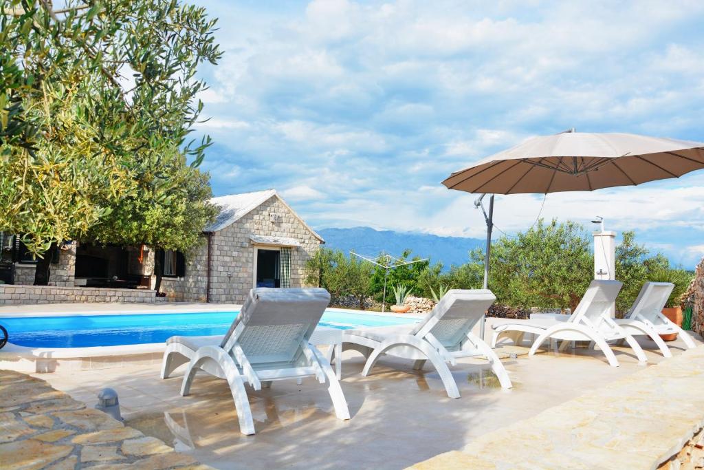 un grupo de sillas y una sombrilla junto a una piscina en Holiday Home Sweet Dreams, en Pučišća