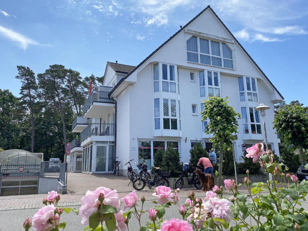 a white building with pink flowers in front of it at Ferienwohnung Ostseeliebe mit Balkon in Baabe