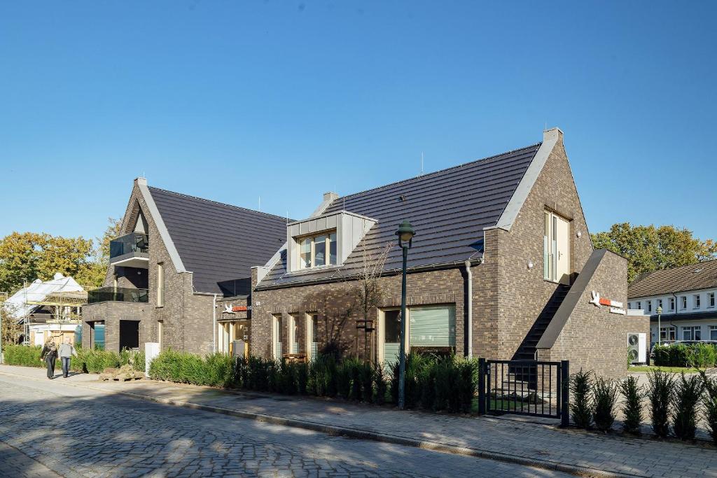 a brick house with a black roof on a street at Ferienwohnung Pinschieter in Born