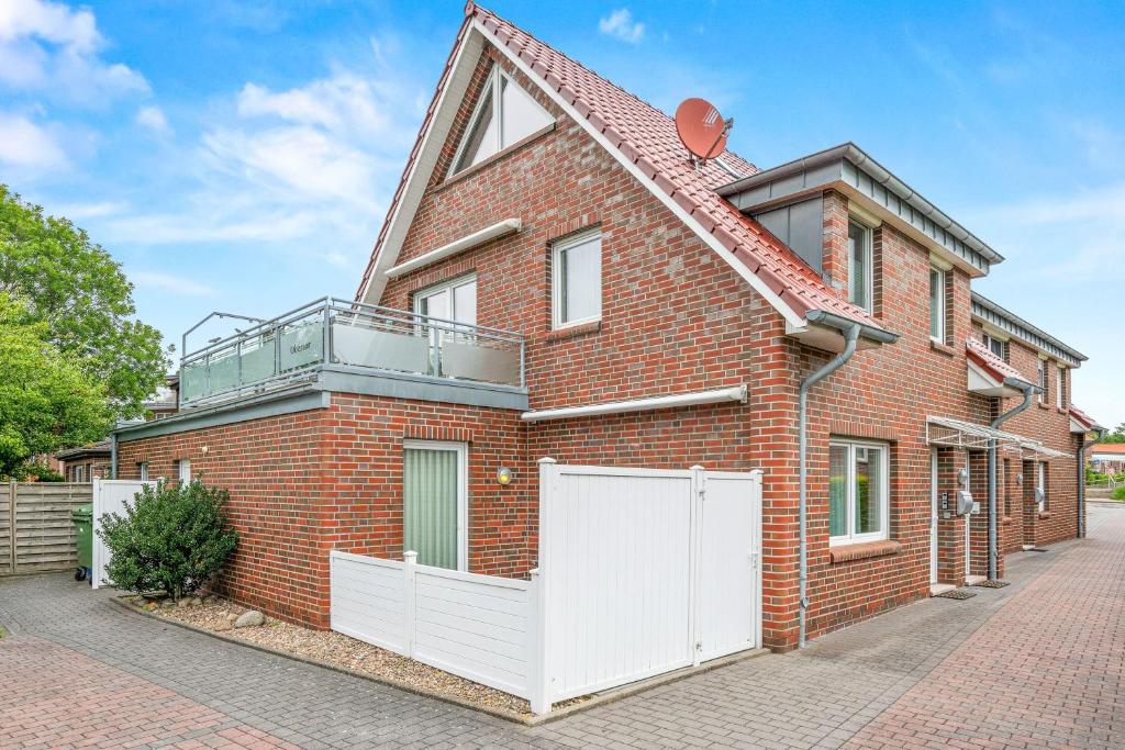 a red brick house with a white fence at Ferienwohnung Hamtor in Bensersiel