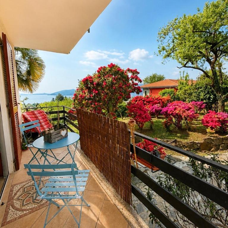 a blue chair on a balcony with pink flowers at Nido vista Lago Maggiore e isole borromee in Cissano
