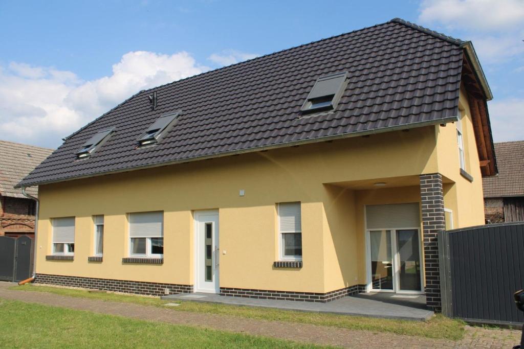 a yellow house with a black roof at Ferienhaus zur Eiche am Dorfanger in Waldow