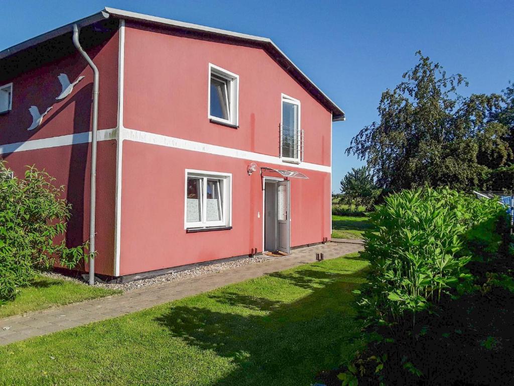 a red and white house with a green yard at Ferienwohnungen am Bach in Marlow
