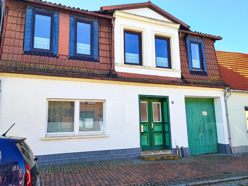 a white house with green doors and a red roof at Ferienwohnung Amelie in Ribnitz-Damgarten