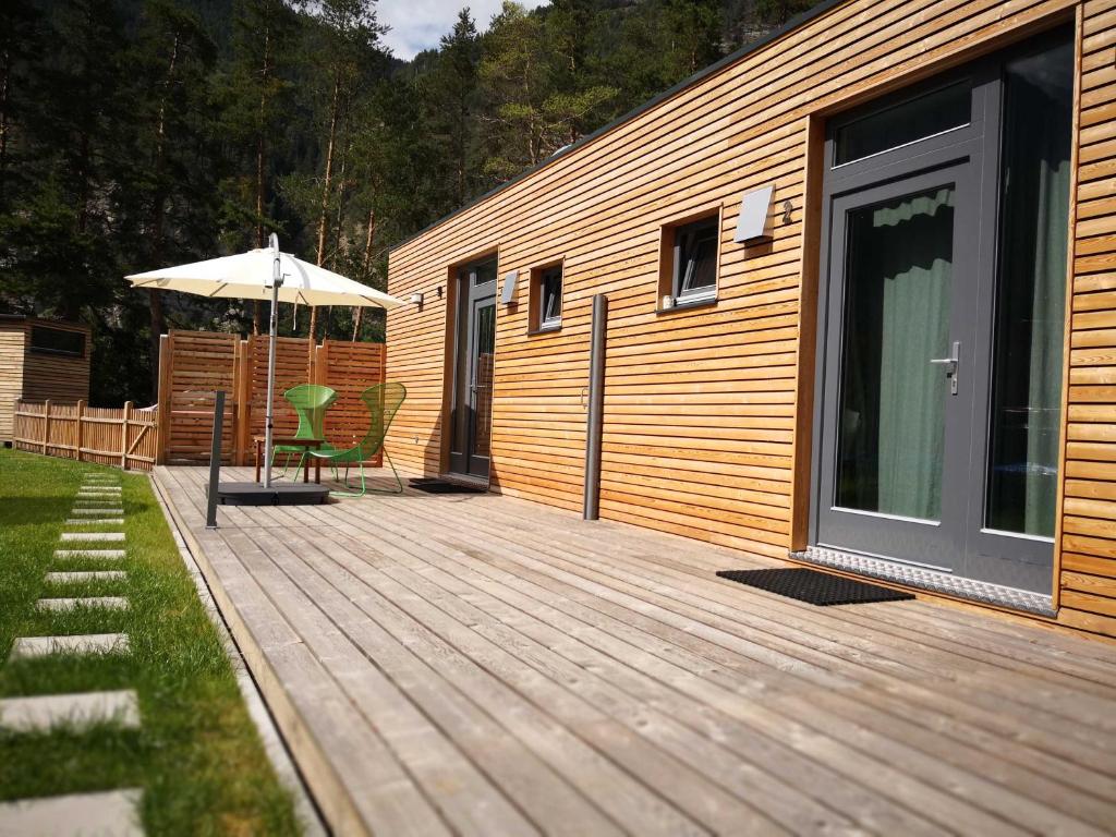 a wooden deck with an umbrella and a table and chairs at FREE Ride cabins in Tösens