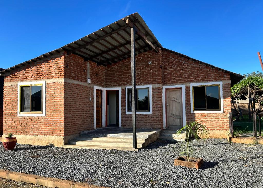 a red brick house with a porch at PRIDE LANDS SAFARI LODGE in Bwakira Juu