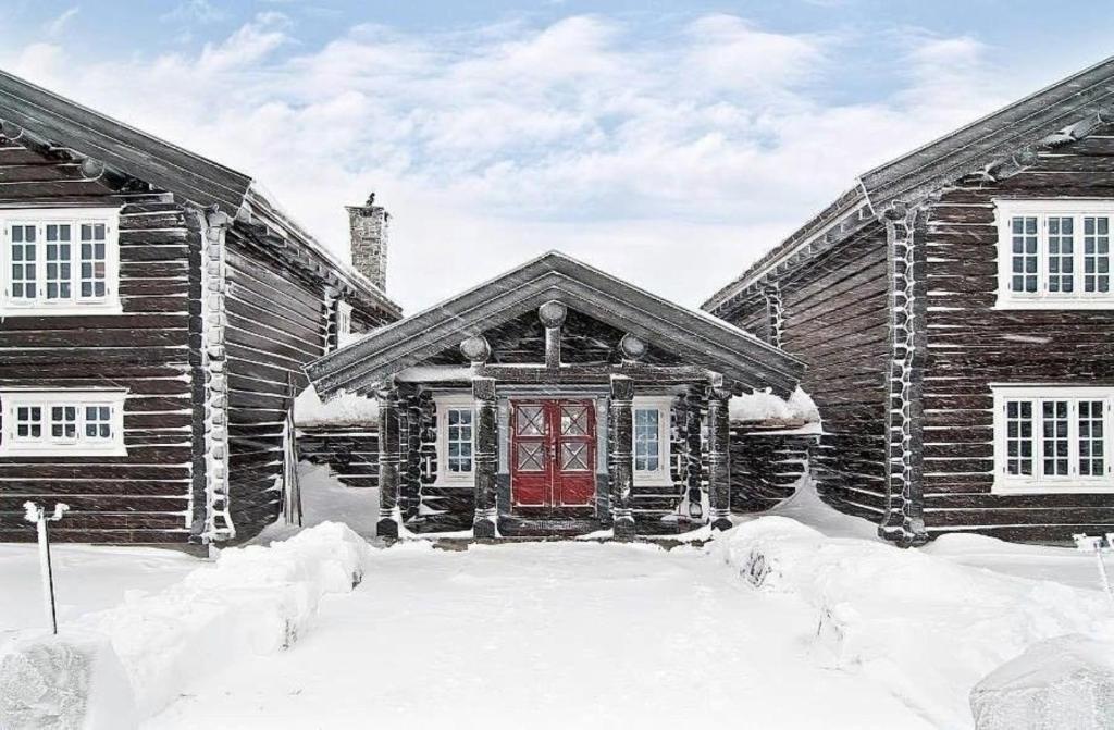 a log cabin with a red door in the snow at Hafjell apartment, Ilsetra in Øyer