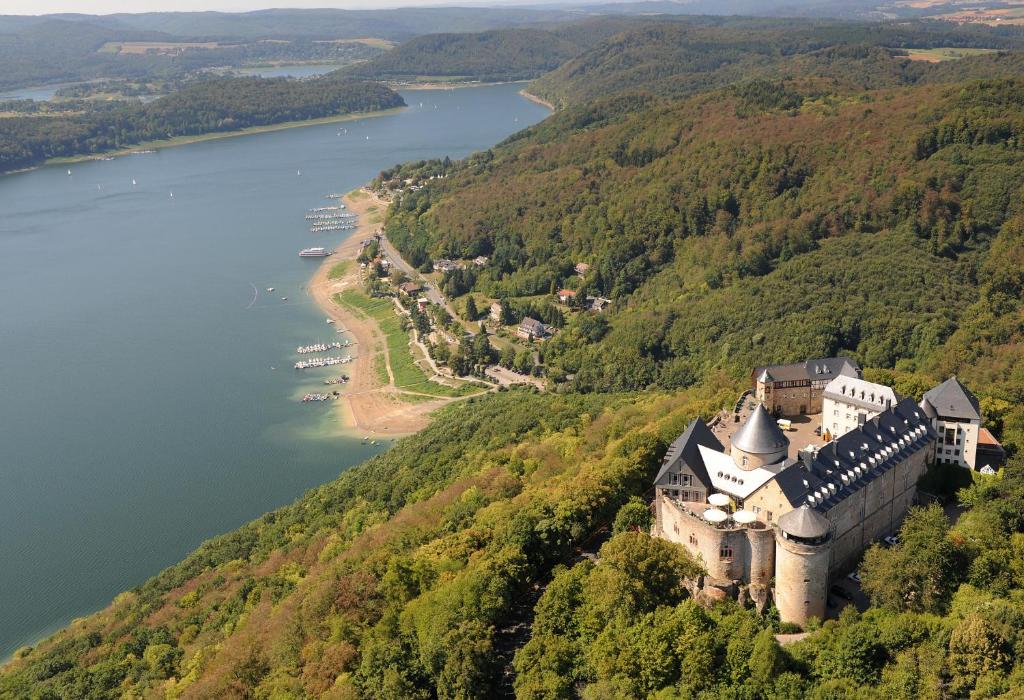 a castle on a hill next to a body of water at Hotel Schloss Waldeck in Waldeck