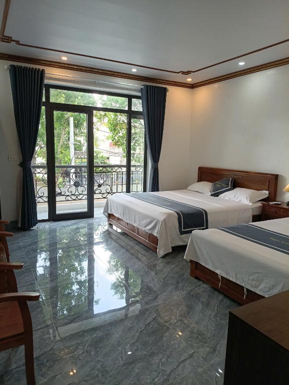 a hotel room with two beds and a balcony at Tam Coc Cozy Hotel in Vũ Lâm