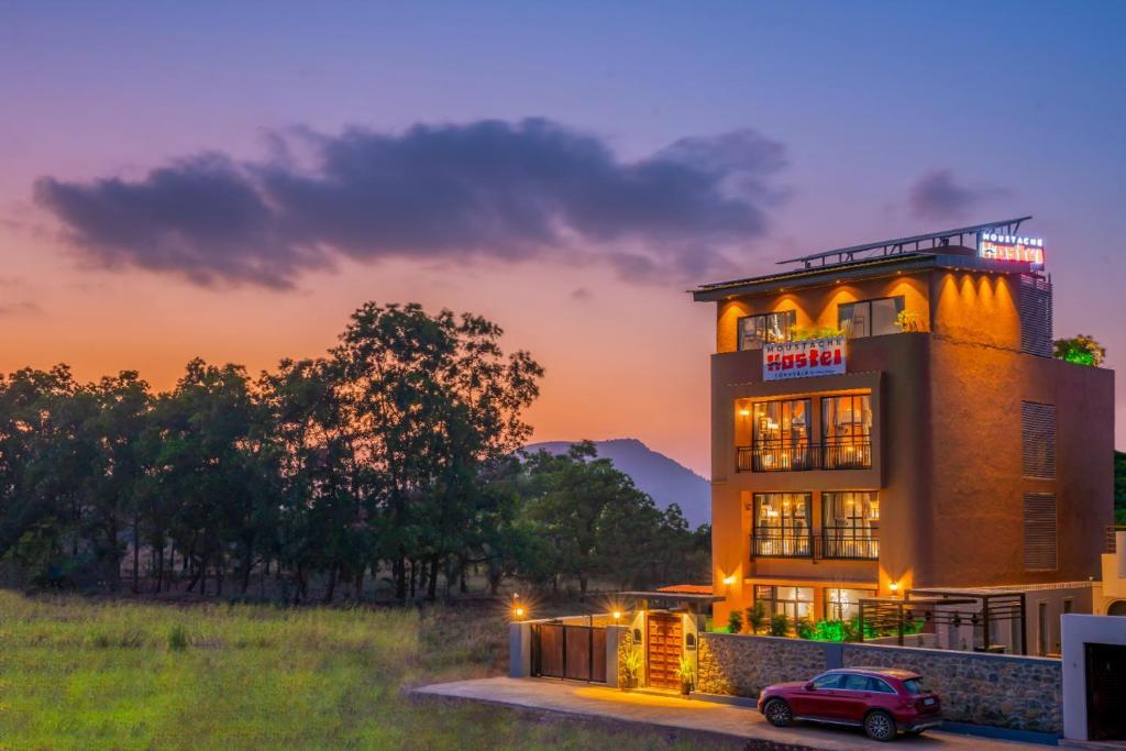 a building with a car parked in front of it at Moustache Hostel Lonavala in Malavli