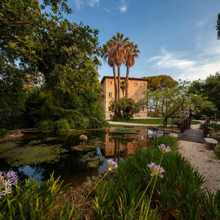 a house with a pond in front of it at Borgo Storico Seghetti Panichi in Castel di Lama