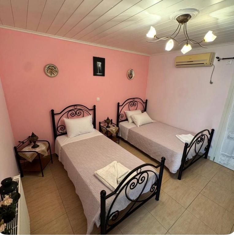 two beds in a room with pink walls at Γιασεμί 5 in Fiskardo