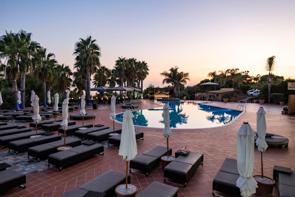 a hotel pool with lounge chairs and umbrellas at Baia Di Ulisse Wellness & Spa in San Leone