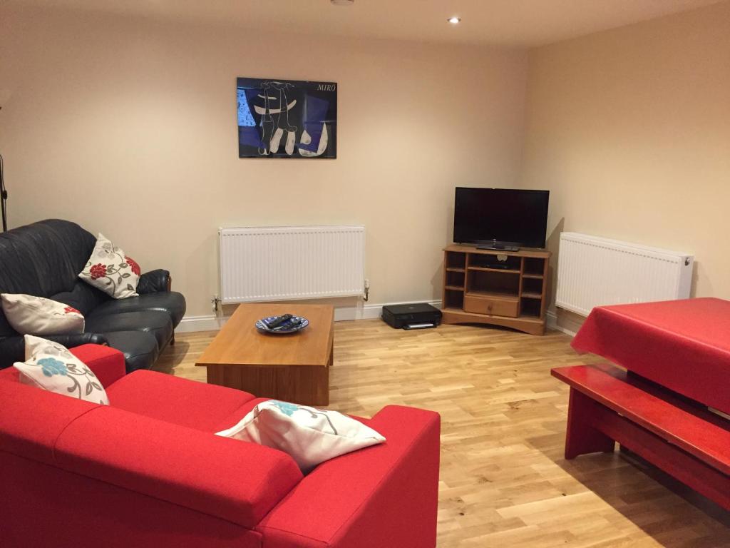 uma sala de estar com um sofá vermelho e uma televisão em The Goldings em Lewes