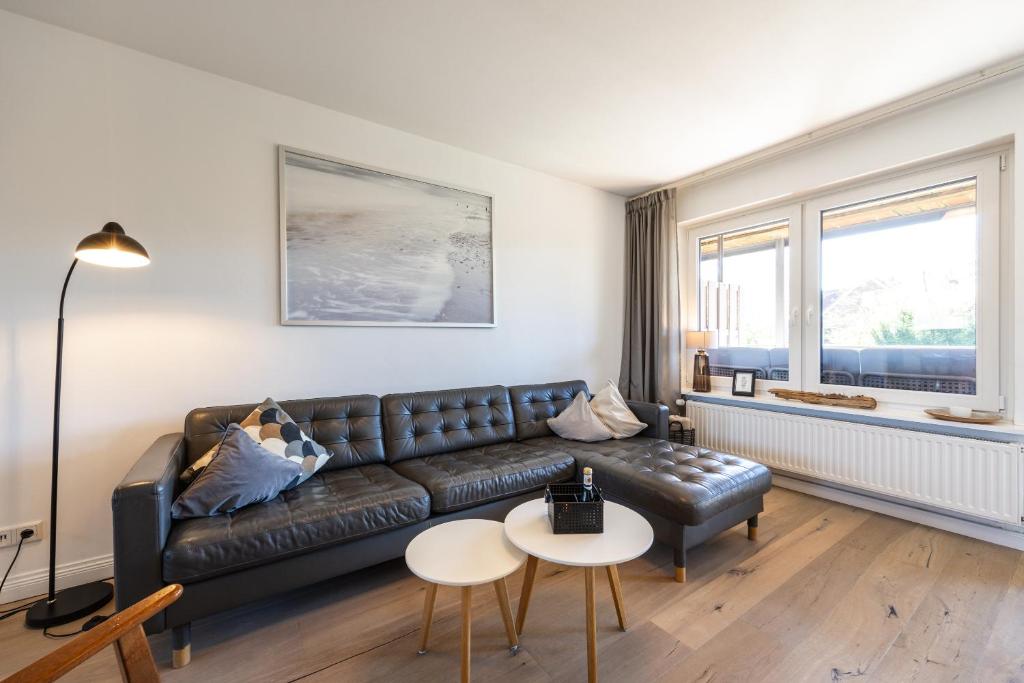 a living room with a leather couch and two tables at Appartementanlage Wieben in Böhl