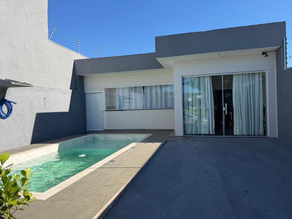 a house with a swimming pool in front of it at casa da piscina e churrasco in Maringá