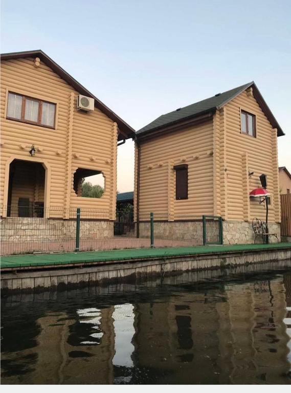 a large wooden house next to a body of water at Дом рыбака Маяки Ватер Сити Днестр in Mayaki